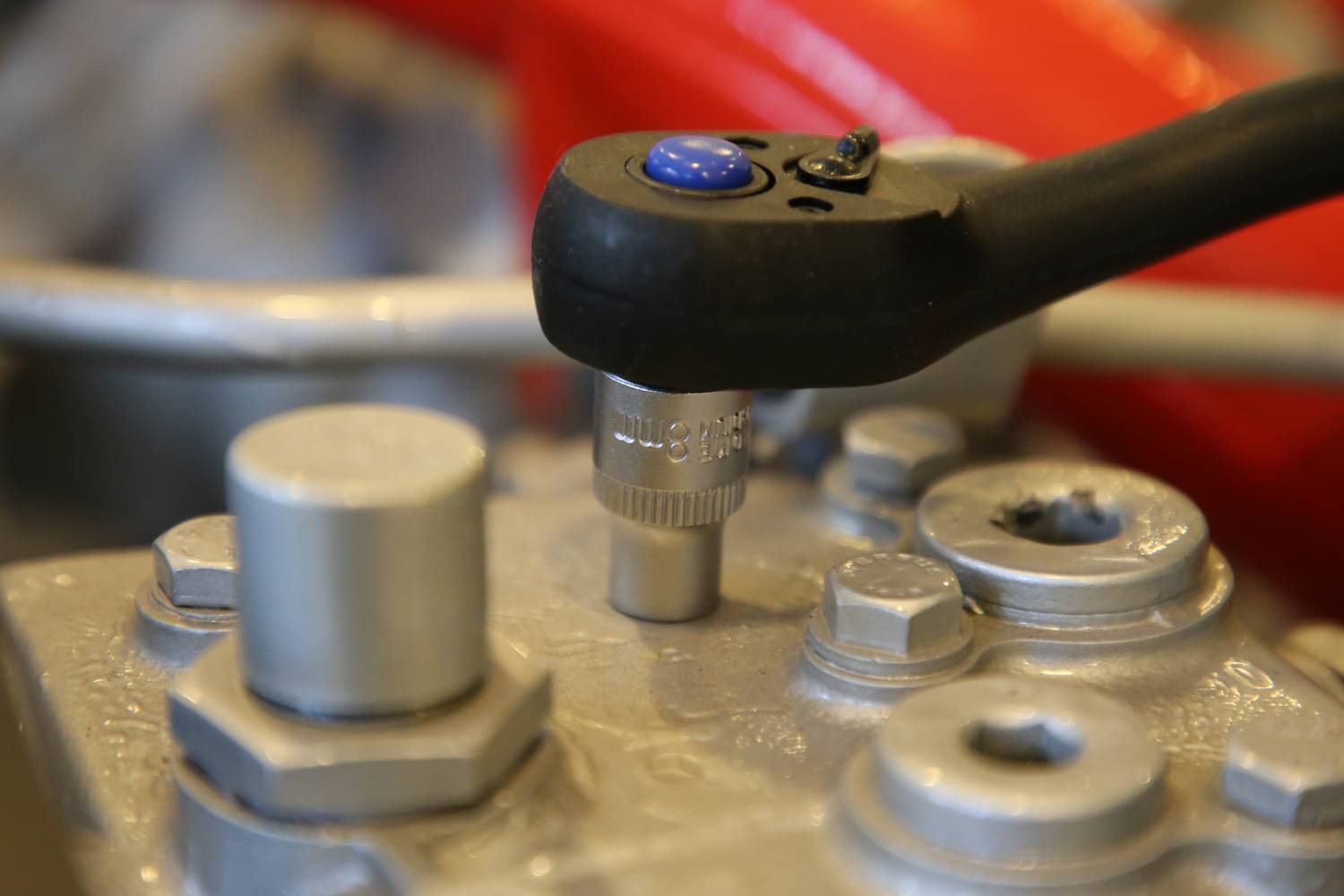 Klucz dynamometryczny dokręca śrubę w elemencie mechanicznym. Zbliżenie ukazuje szczegóły połączeń metalowych.