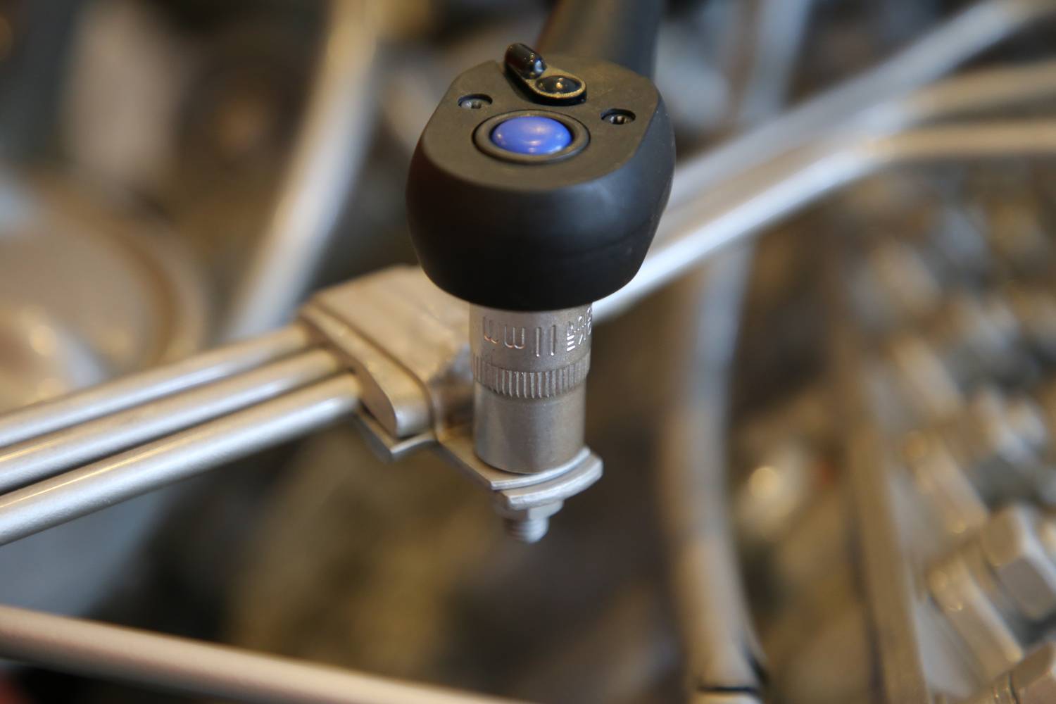 Zbliżenie klucza dynamometrycznego zamocowanego na śrubie. Narzędzie jest używane w środowisku technicznym.