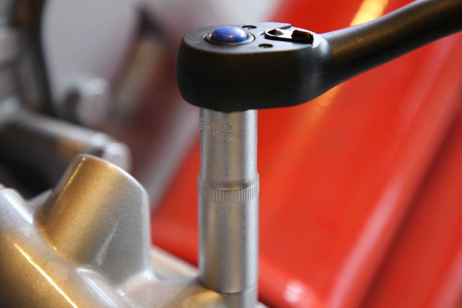 Zbliżenie klucza dynamometrycznego pracującego na metalowej powierzchni. Narzędzie wyświetla niebieskie wskazanie.