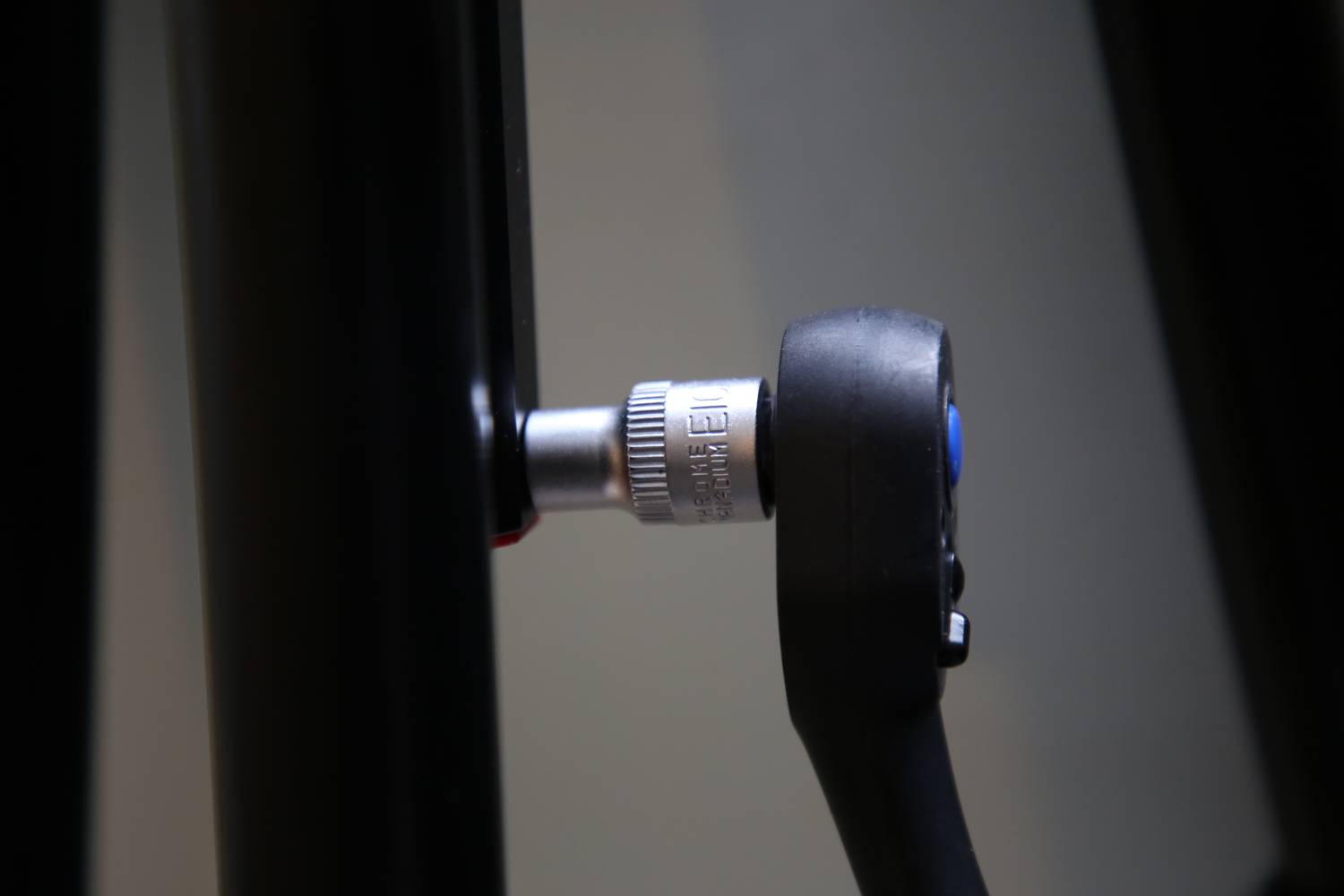 Zbliżenie klucza płaskiego, który jest dokręcany do metalowego pręta. Przedstawia przykład użycia narzędzia.