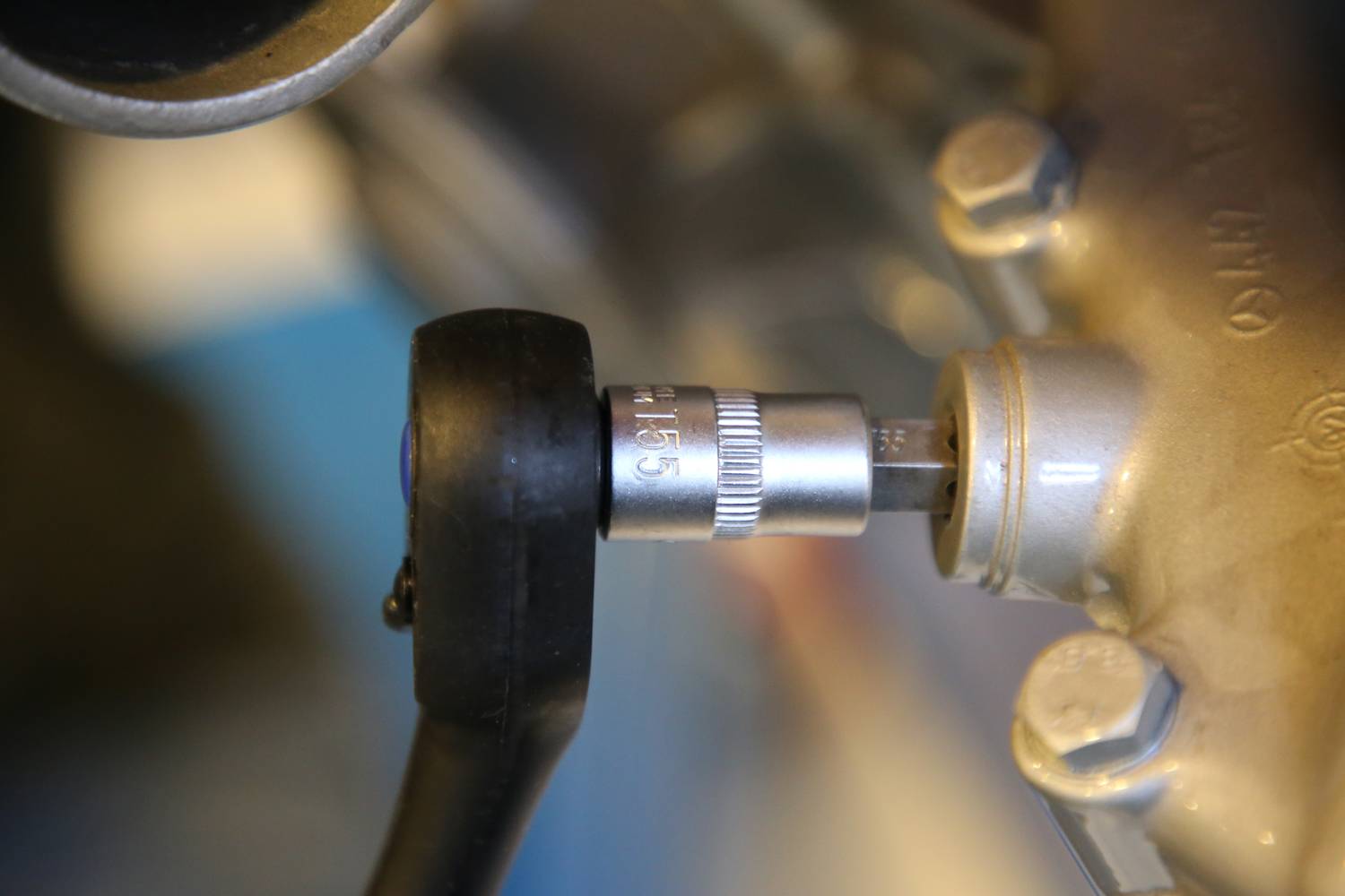 Zbliżenie klucza dynamometrycznego dokręcającego śrubę na metalowym obiekcie. Klucz wskazuje wartość '116,5'.