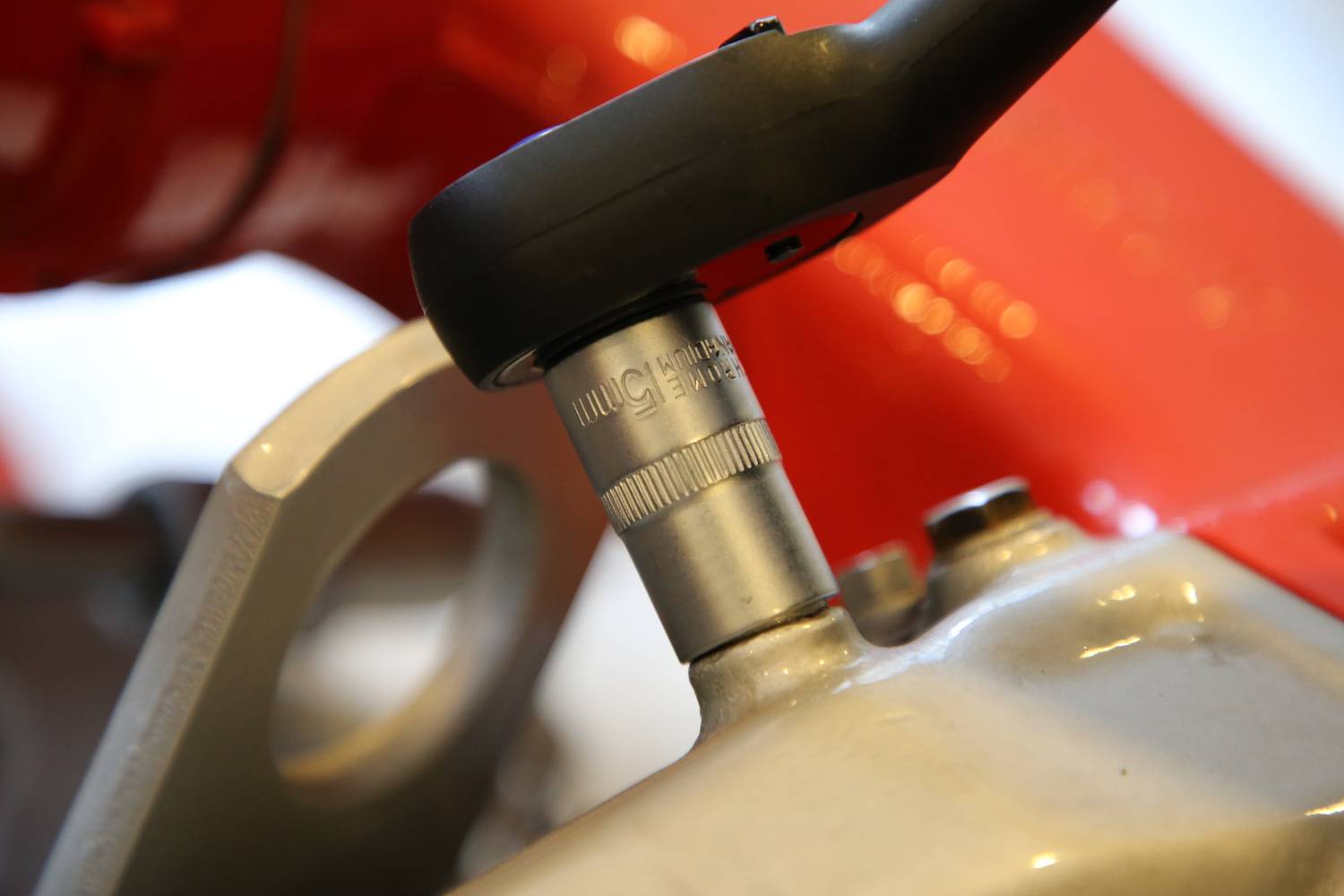 Zapięcie rowerowe jest przymocowane do czerwonej ramy roweru. Zdjęcie przedstawia zbliżenie mechanizmu zamykającego oraz ramy.