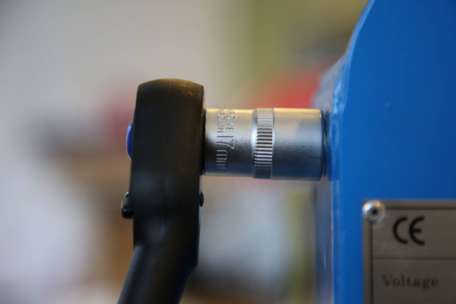 Czarny dźwignik jest włożony do niebieskiej maszyny. Tuż obok po prawej stronie znajduje się srebrny element łączący.