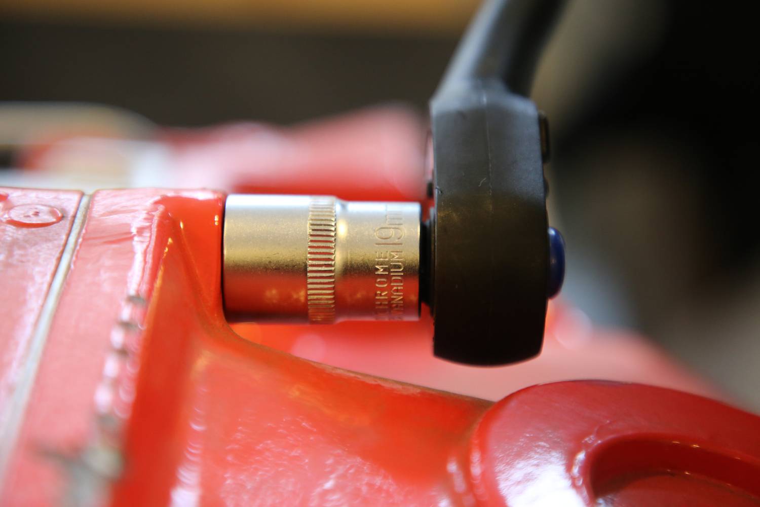 Zbliżenie czerwonego narzędzia z czarną rękojeścią, które ukazuje srebrny mechanizm. Fokus spoczywa na połączeniu.