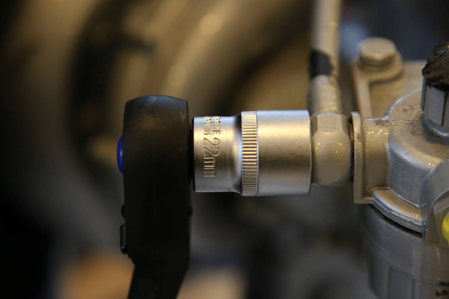 Zbliżenie metalowego zaworu ze sterowaniem czarnym pokrętłem, prawdopodobnie będącego częścią instalacji maszynowej lub rurociągu.