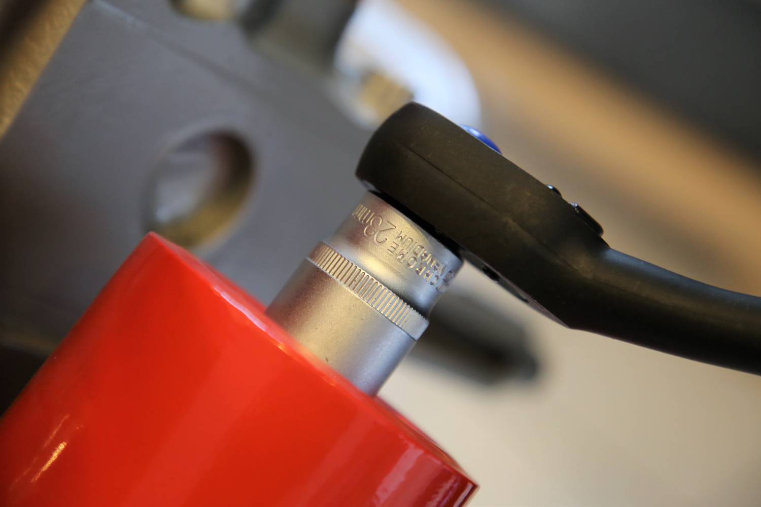 Zbliżenie klucza, który dokręca śrubę na czerwonej metalowej ramie. Narzędzia i precyzyjna praca w centrum uwagi.