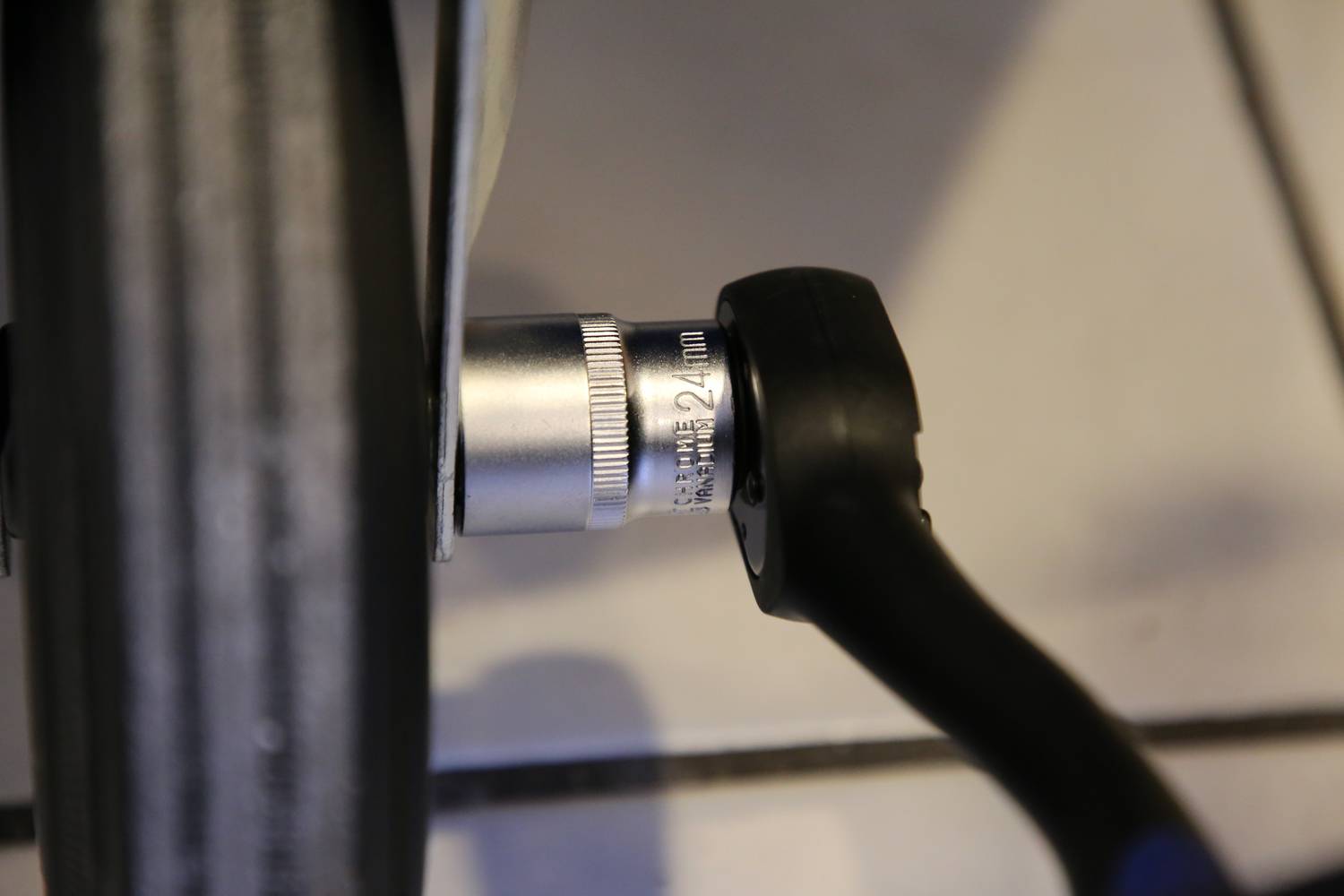 Klucz nastawny jest przyłożony do srebrnej nakrętki na czarnym ramieniu szprychy roweru.