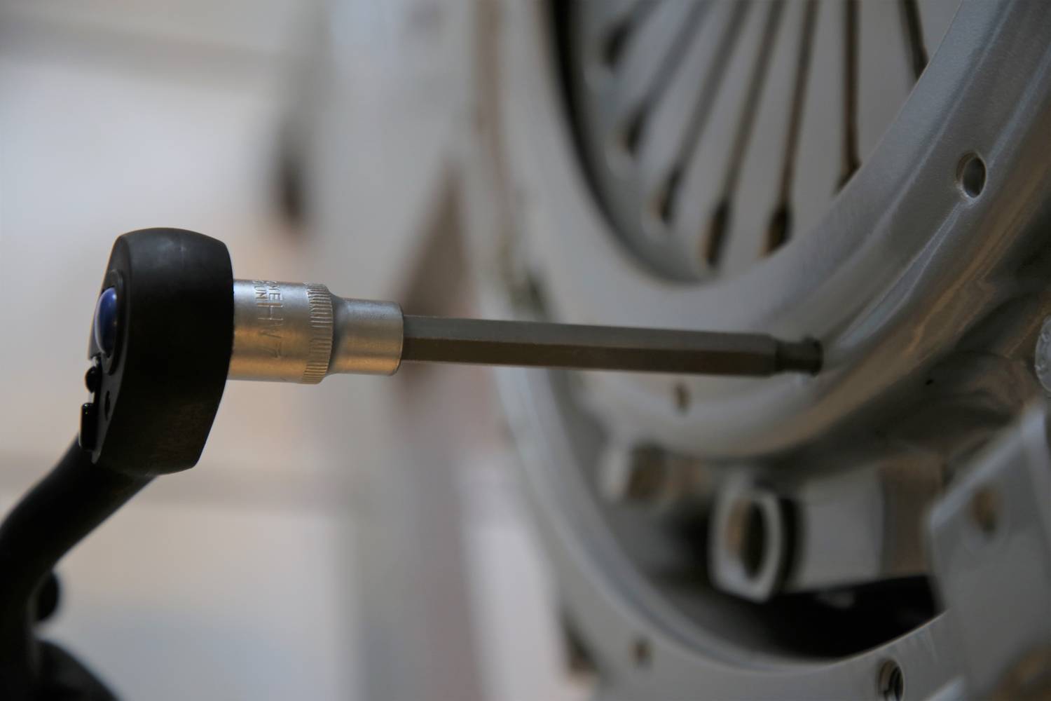 Zbliżenie narzędzia dokręcającego śrubę przy metalowym elemencie maszyny, prawdopodobnie podczas procesu montażu technicznego.