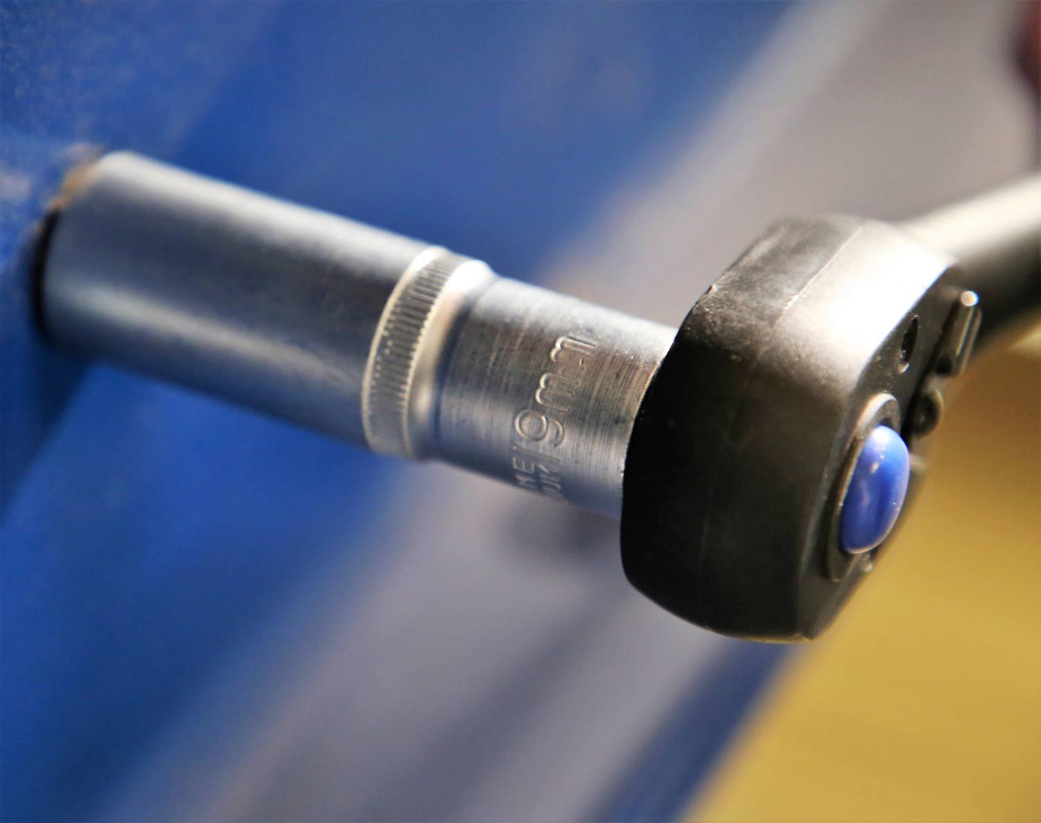 Zbliżenie mikrometru mierzącego obiekt. Przyrząd wskazuje '19 mm'.