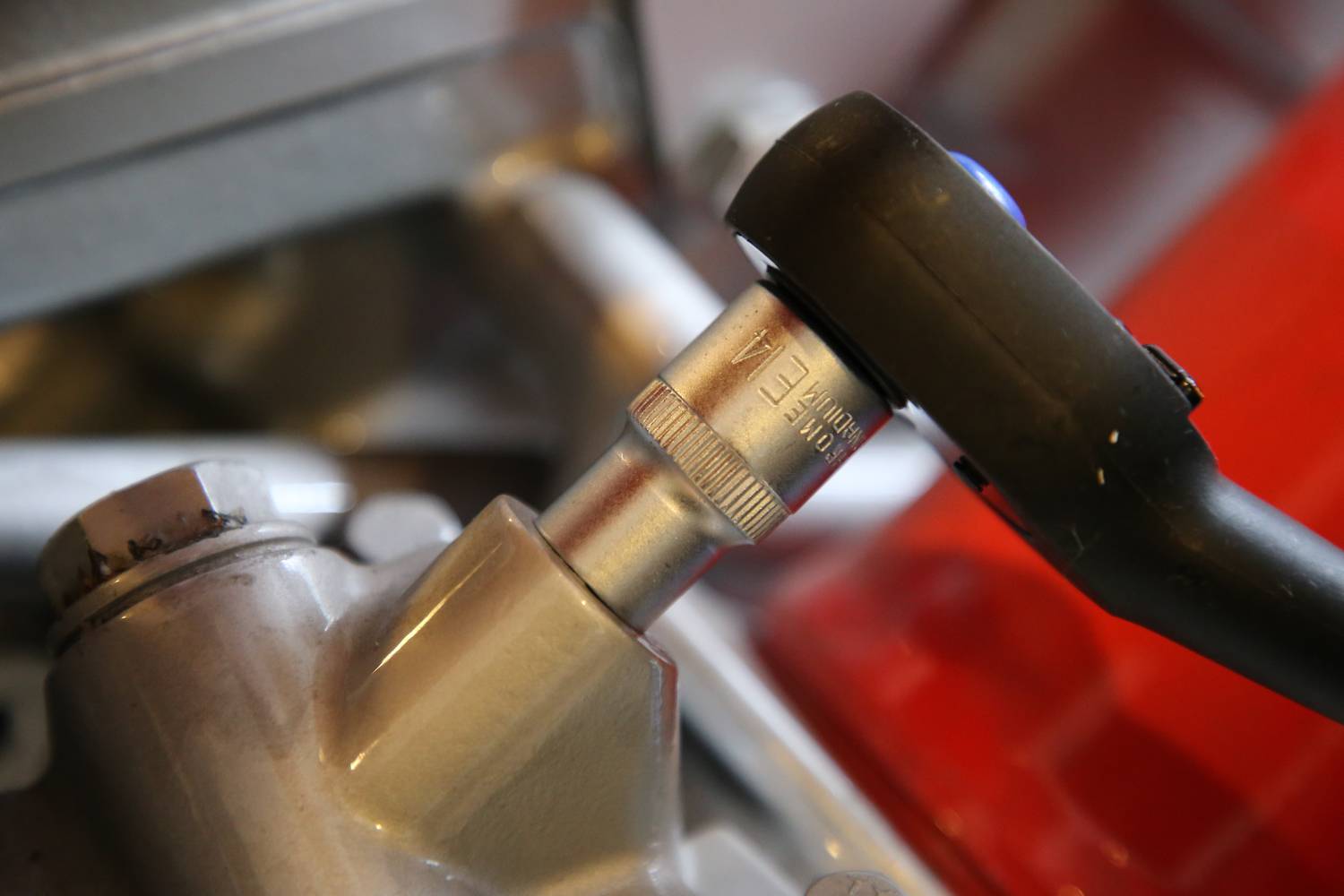 Klucz do nakrętek obraca śrubę na metalowej powierzchni, która wydaje się być częścią jakiejś maszyny.