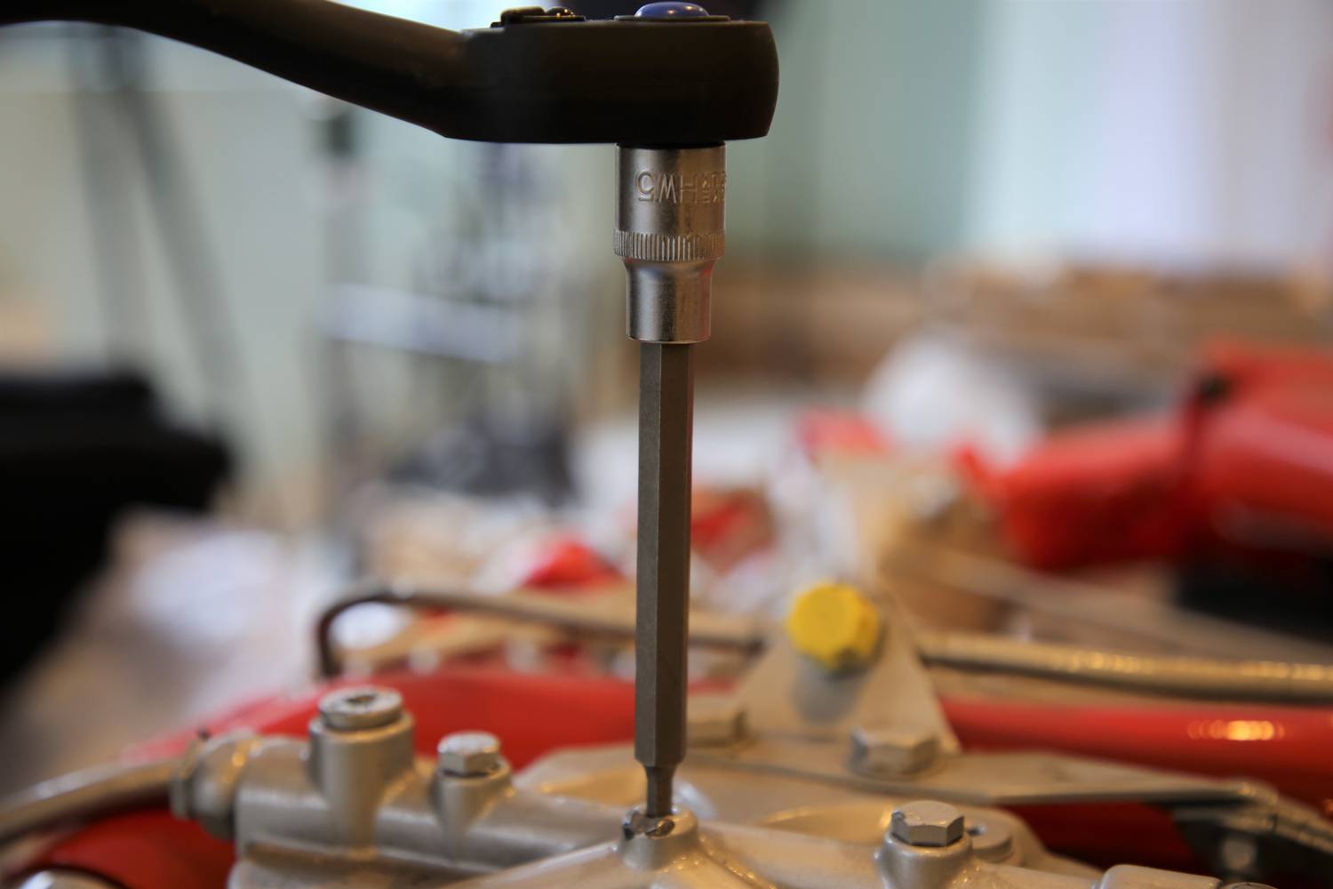 Przegub krzyżowy jest dokręcany kluczem. W tle widać rozmyte wyposażenie warsztatu.