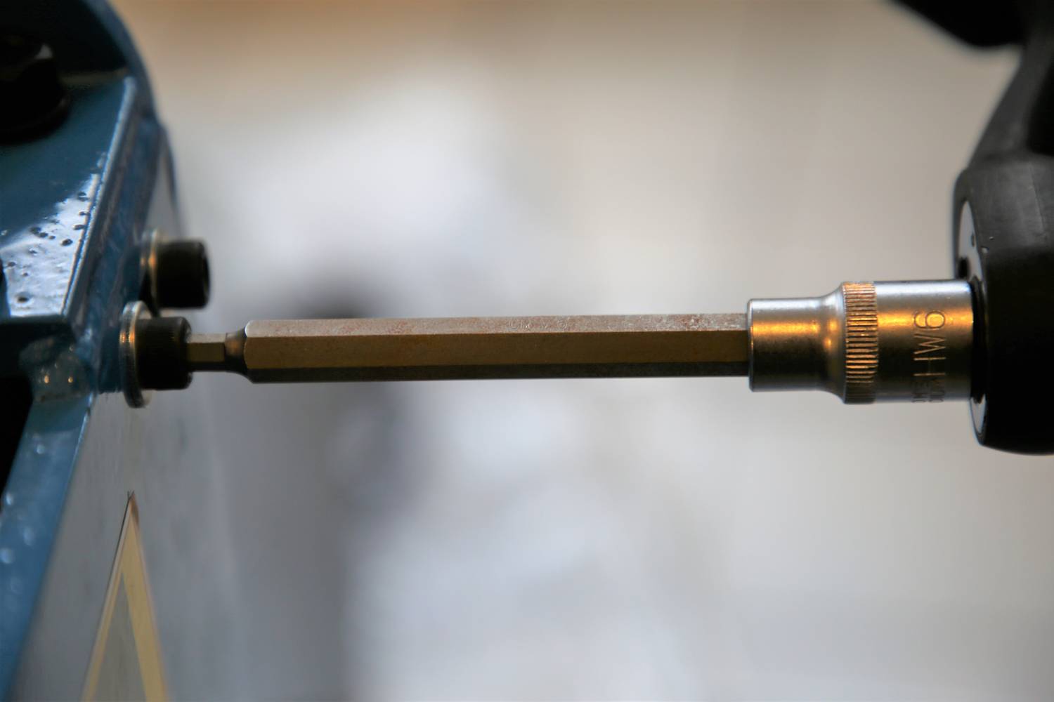 Śrubokręt służy do wkręcania śruby w urządzenie metalowe. Fokus jest na główce śrubokręta.