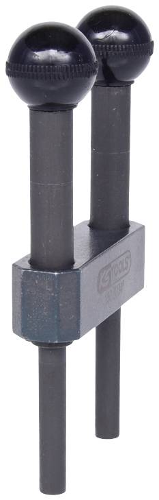 Dwie czarne, kuliste blokady wałków rozrządu zamocowane na metalowym uchwycie, widoczne podczas naprawy silnika.