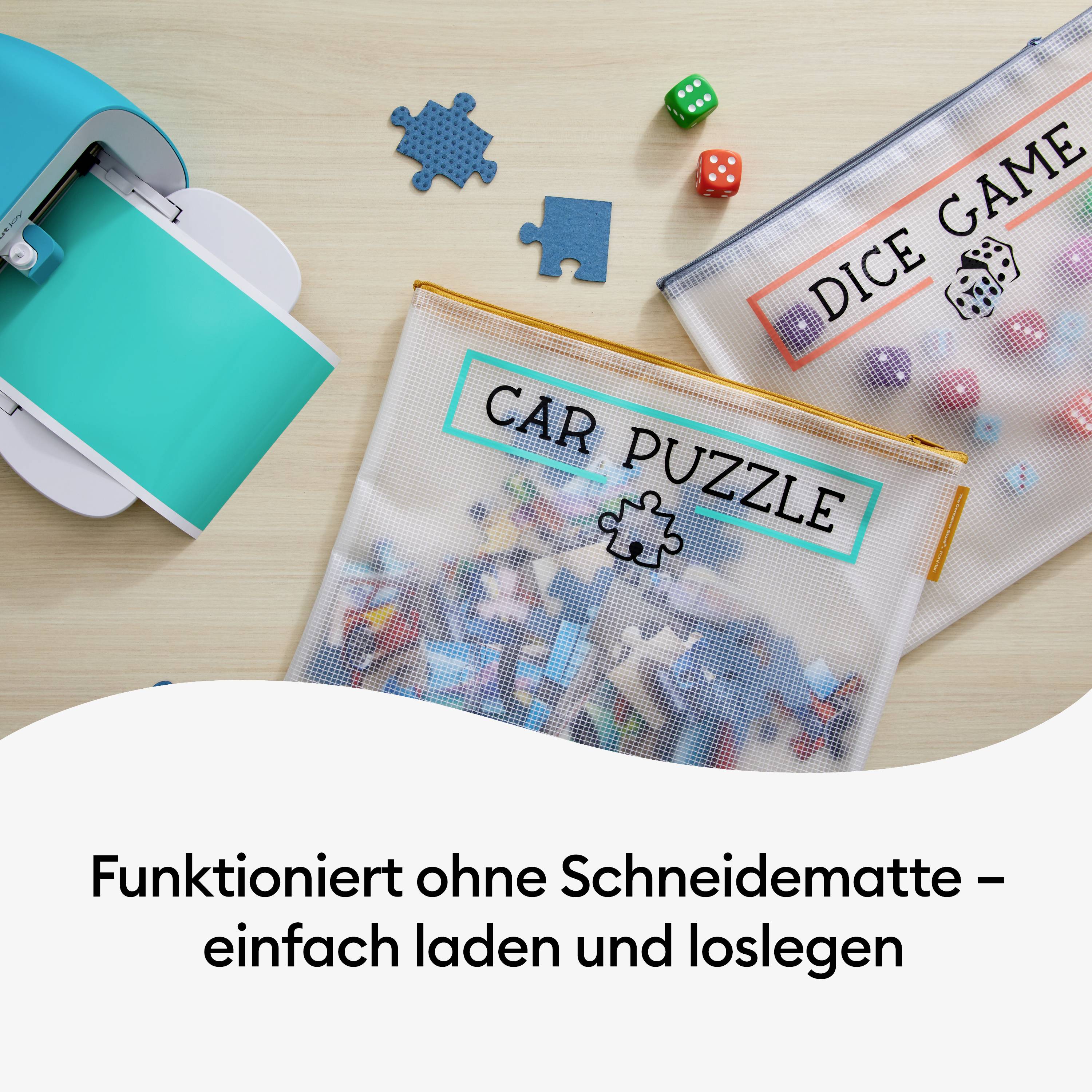 Stół z drukarką, dwie przezroczyste torby oznaczone napisami 'Car Puzzle' i 'Dice Game' oraz kilka małych elementów gry. Poniżej tekst: 'Działa bez maty do cięcia – po prostu załaduj i zacznij grać'.