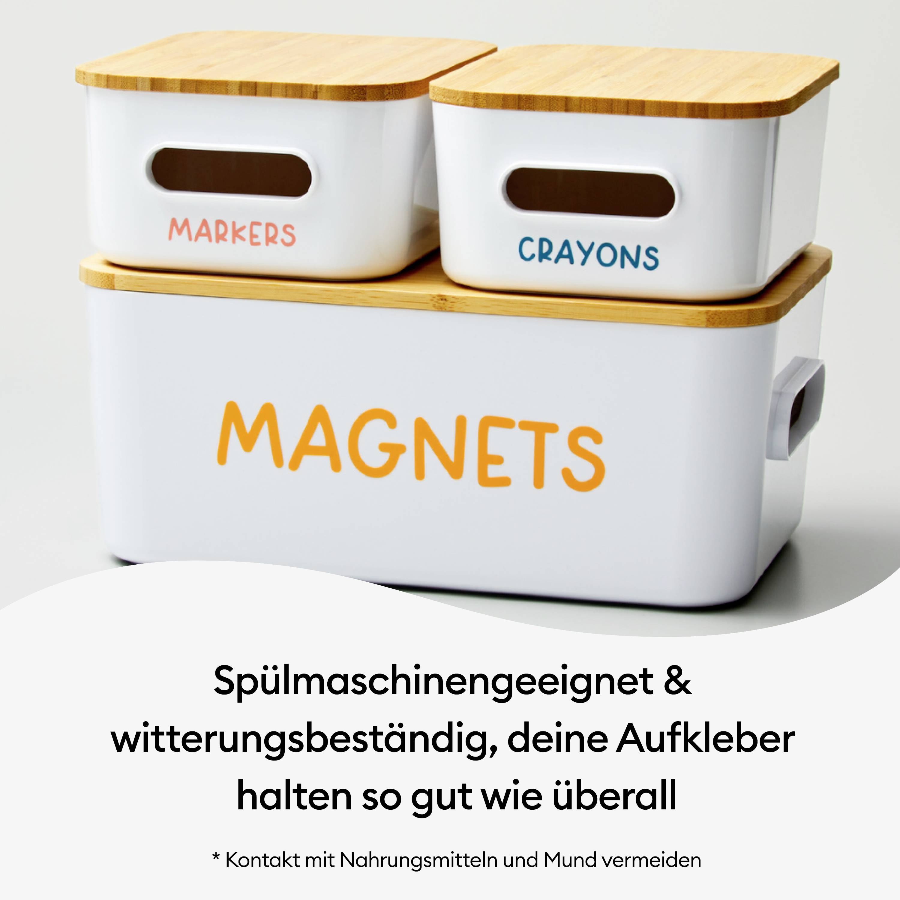 Dwa białe pojemniki z drewnianymi pokrywkami, oznaczone napisami 'Markers' i 'Crayons', stoją jeden na drugim. Tekst poniżej reklamuje wytrzymałe naklejki.