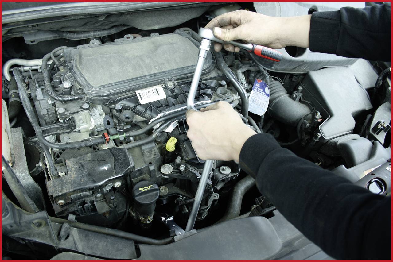 Osoba naprawia silnik samochodu kluczem hydraulicznym.