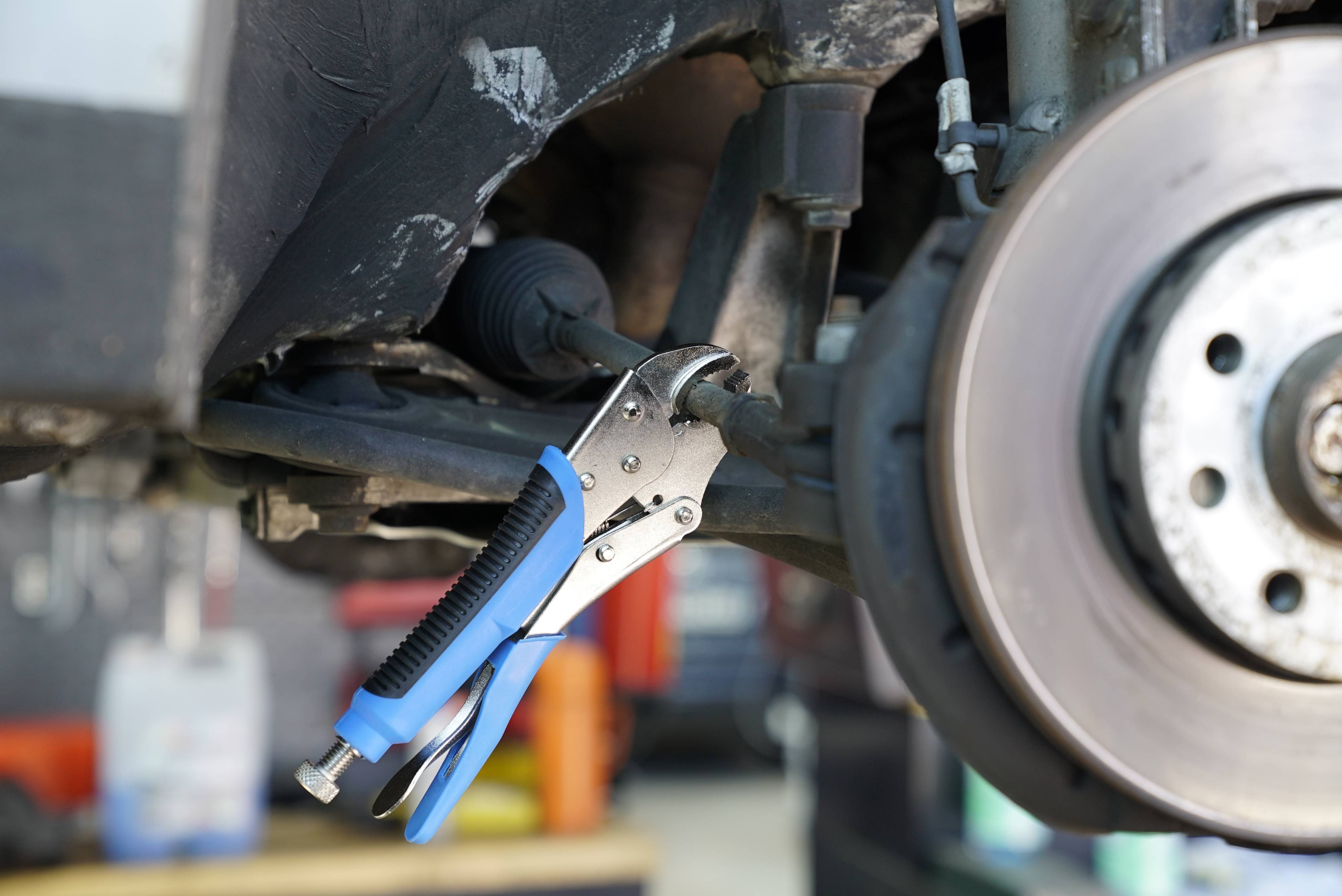 Szczypce do połączeń krzyżowych samochodowych są zamocowane na elemencie gwintowanym w pobliżu otwartego systemu hamulcowego samochodu.