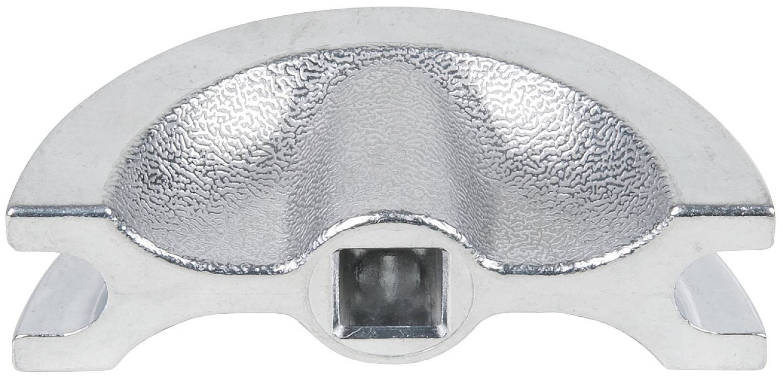 Kawałek metalu w kształcie półkola, lśniący, o powierzchni nakrawanej i kwadratowym wycięciu pośrodku.