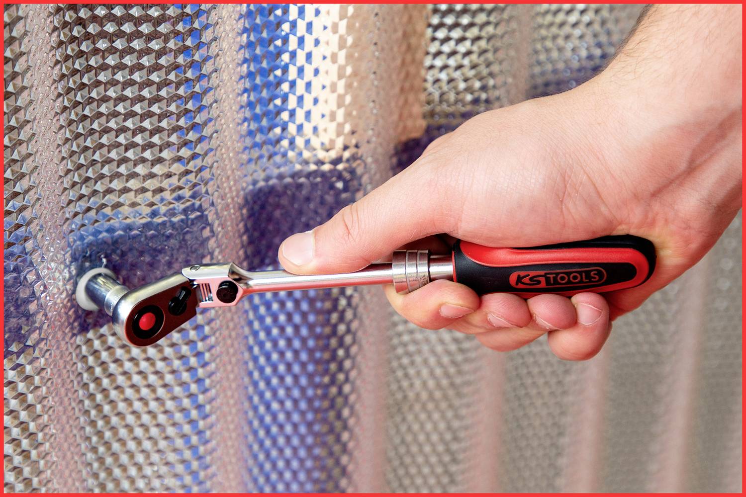 Ręka używa wkrętaka z grzechotką do dokręcania śruby na strukturyzowanej metalowej powierzchni.