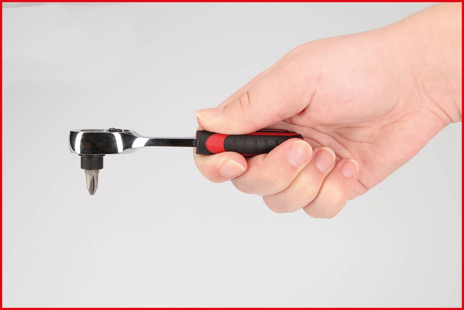 Jedna ręka trzyma grzechotkę z czarnym uchwytem i końcówką nasadkową.