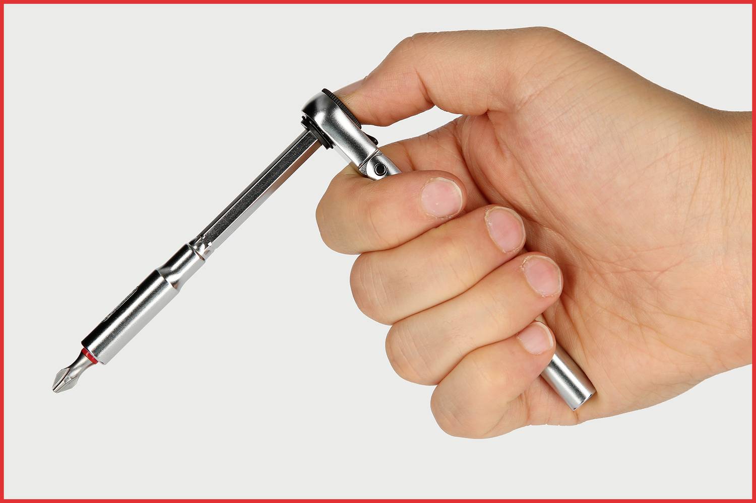 Ręka trzyma śrubokręt z mechanizmem grzechotki. Grzechotka jest ustawiona w pozycji, która umożliwia elastyczny ruch obrotowy.