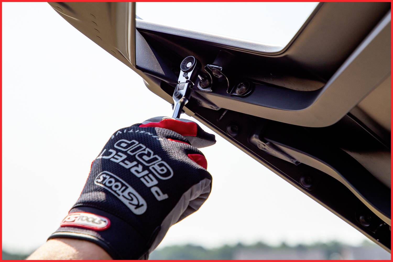 Osoba naprawia część dachu pojazdu wkrętakiem, podczas gdy ma na ręce rękawicę.