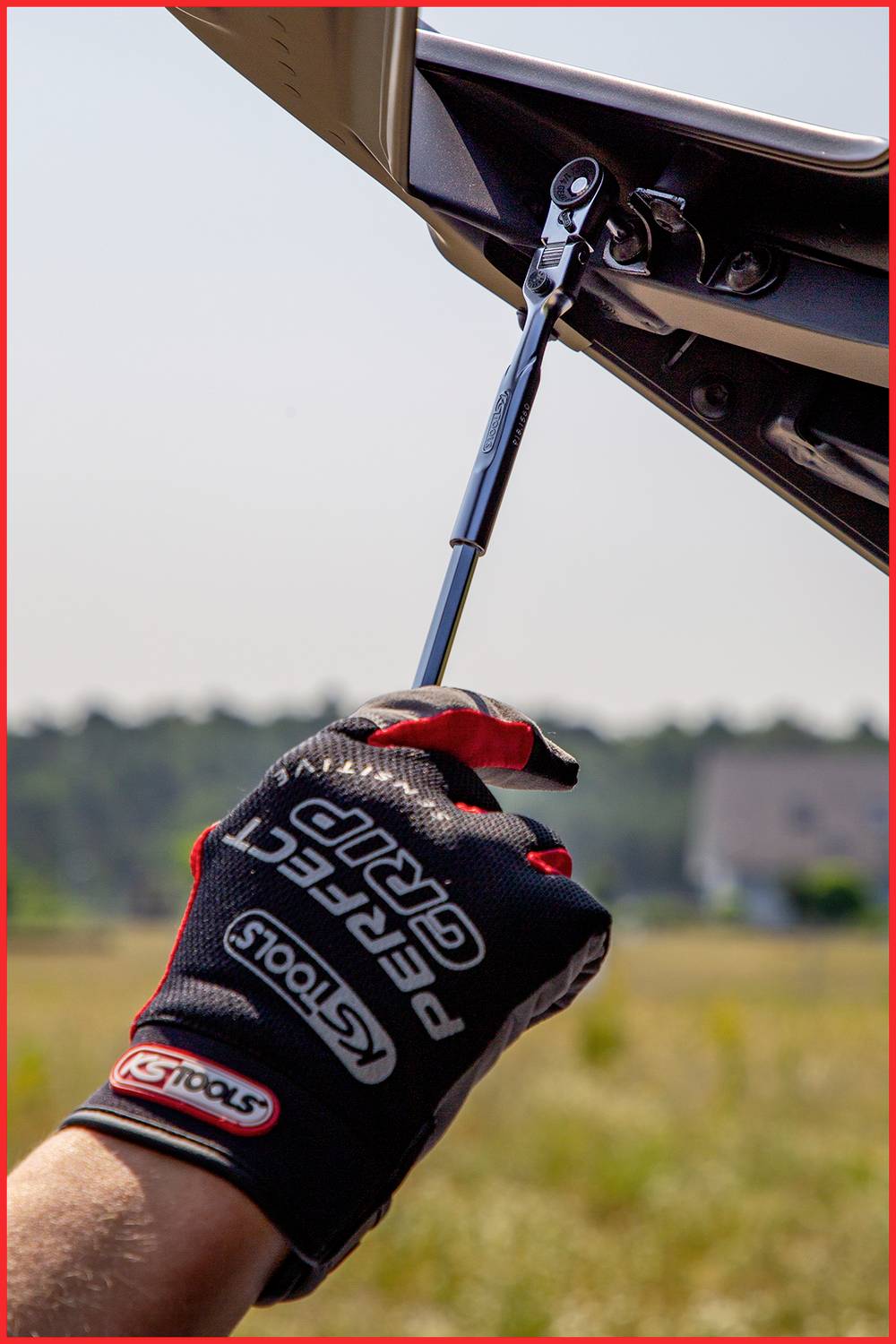 Osoba dokręca śrubę kluczem dynamometrycznym na motocyklu. Osoba jest w rękawicach.