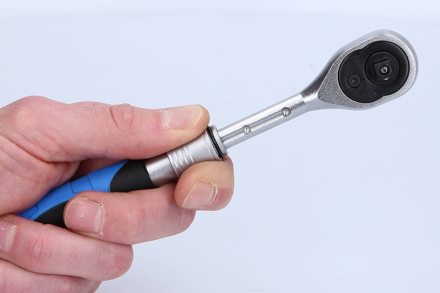 Dłoń trzyma klucz nasadowy z niebieskim uchwytem, używany do dokręcania śrub i nakrętek.