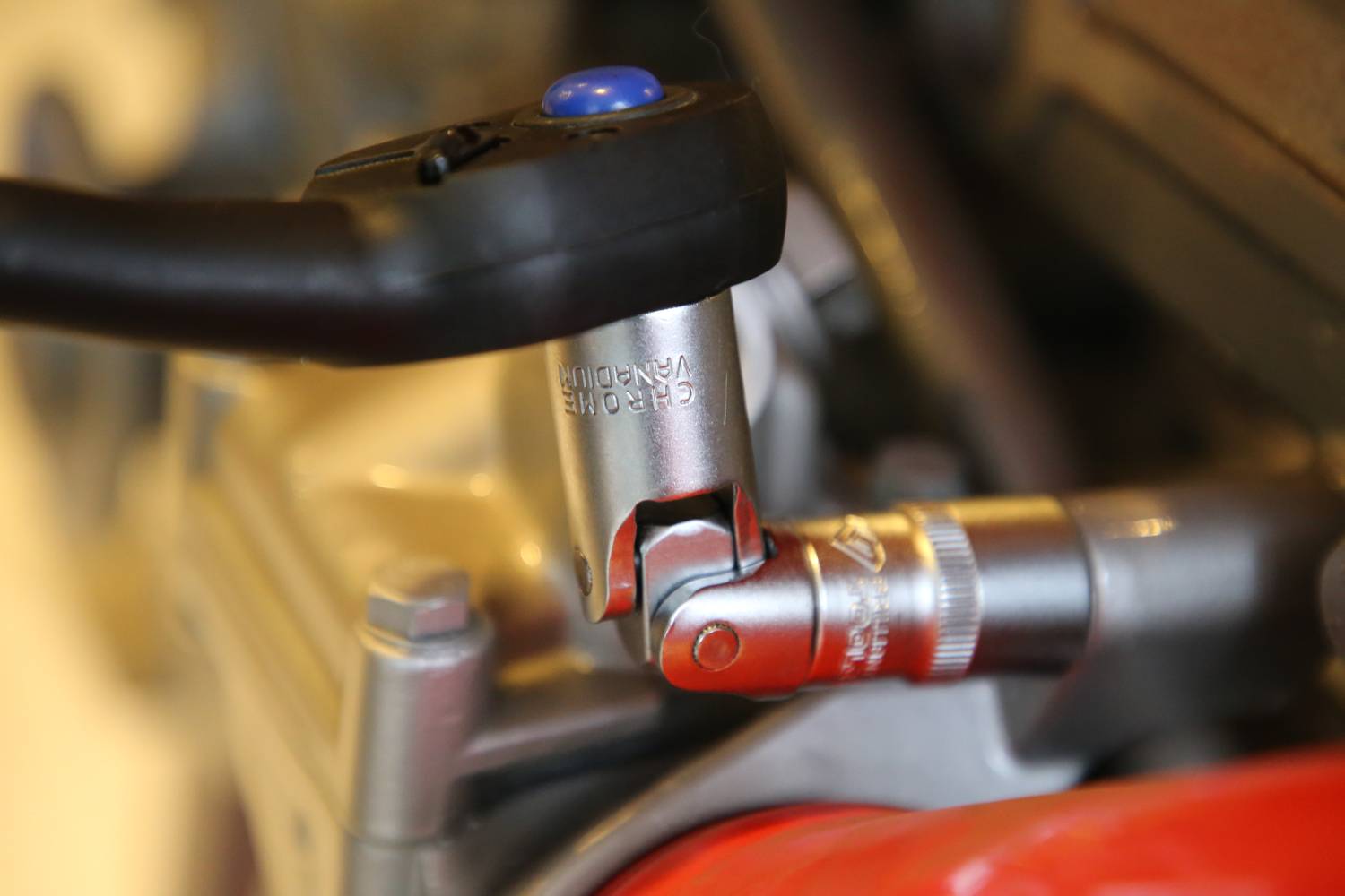 Srebrny klucz dynamometryczny z niebieskim przyciskiem jest używany do zamocowania śruby na metalowym urządzeniu.