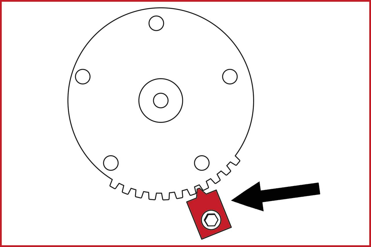 Koło zębate z czerwonym oznaczeniem. Czarna strzałka wskazuje na oznaczenie znajdujące się na krawędzi koła zębatego.