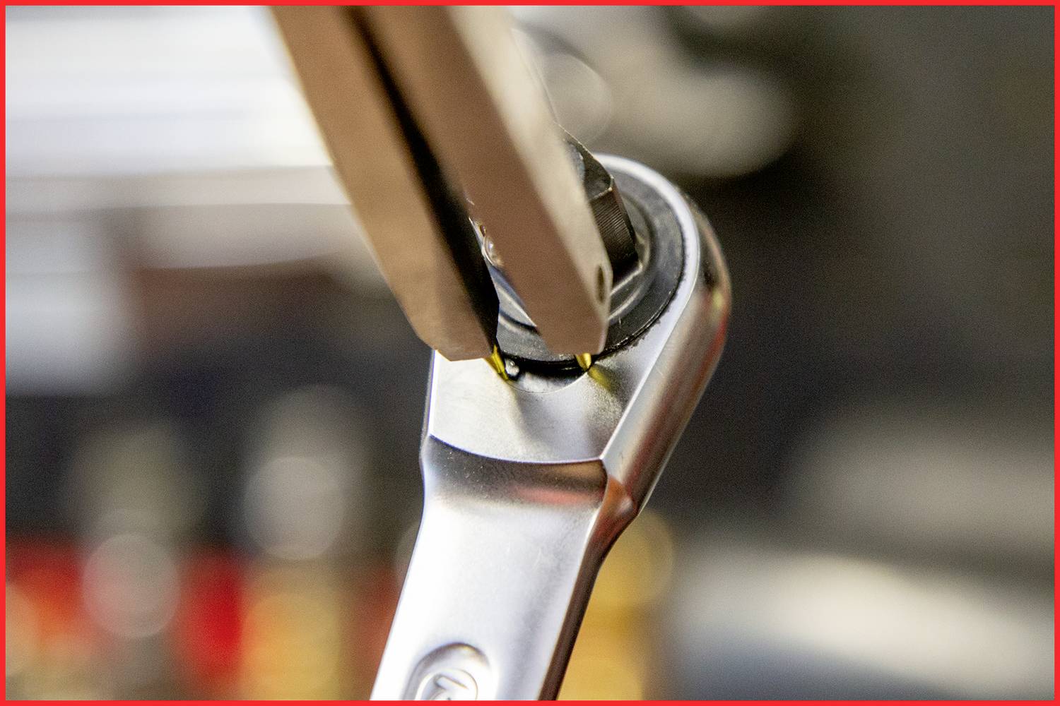 Zbliżenie klucza zakładanego na nakrętkę podczas dokręcania. Fokus jest na interakcji między narzędziem a nakrętką.