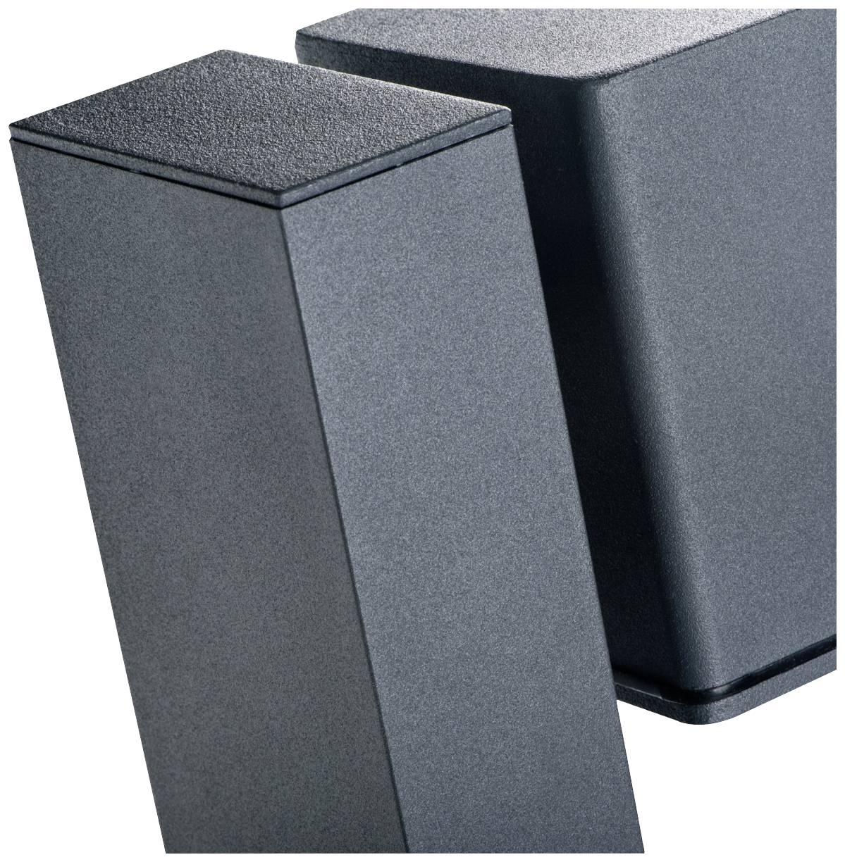 Dwa czarne, prostopadłościenne głośniki o minimalistycznym designie, ustawione obok siebie pod kątem prostym.