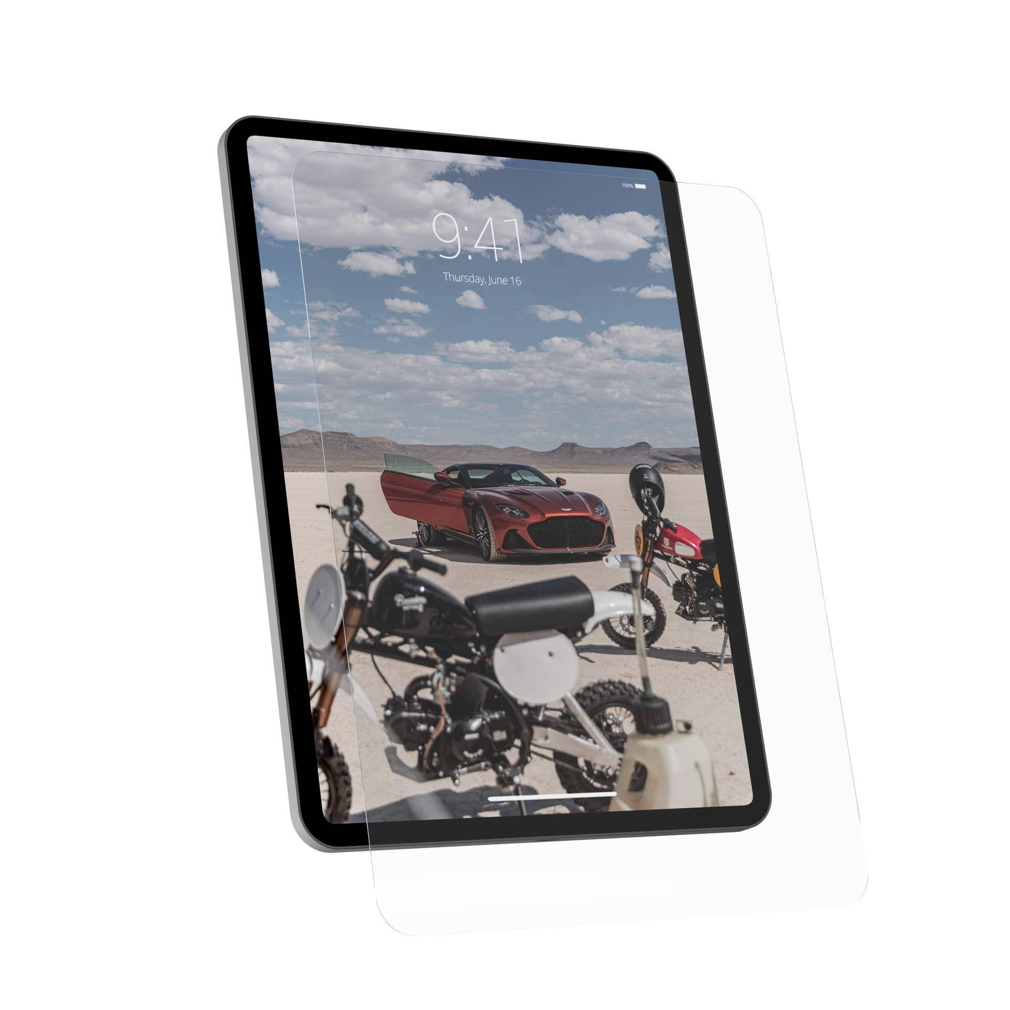 Tablet iPad z podniesionym ekranem wyświetla obraz pustyni z czerwonym samochodem i kilkoma motocyklami na pierwszym planie.