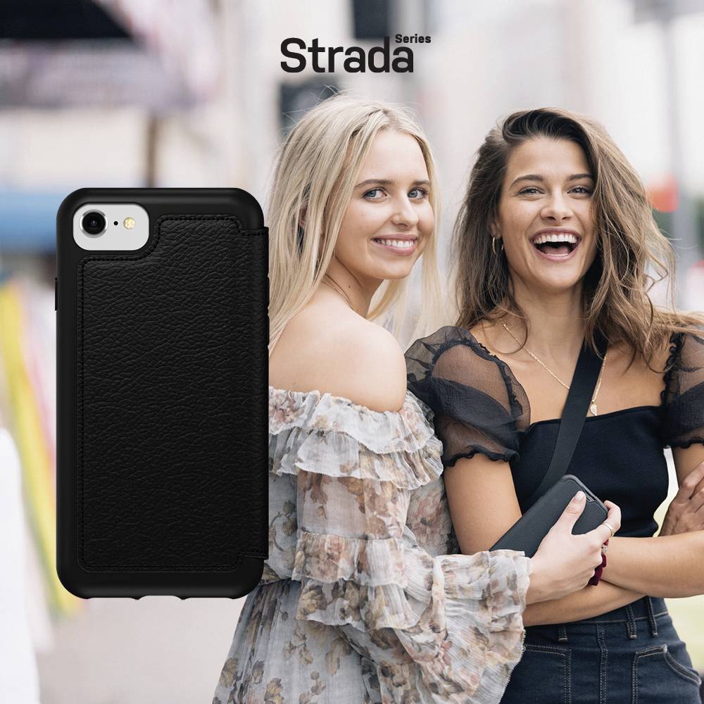 Dwie uśmiechnięte kobiety w letnim stroju radośnie się przytulają na tle rozmytego miejskiego krajobrazu.