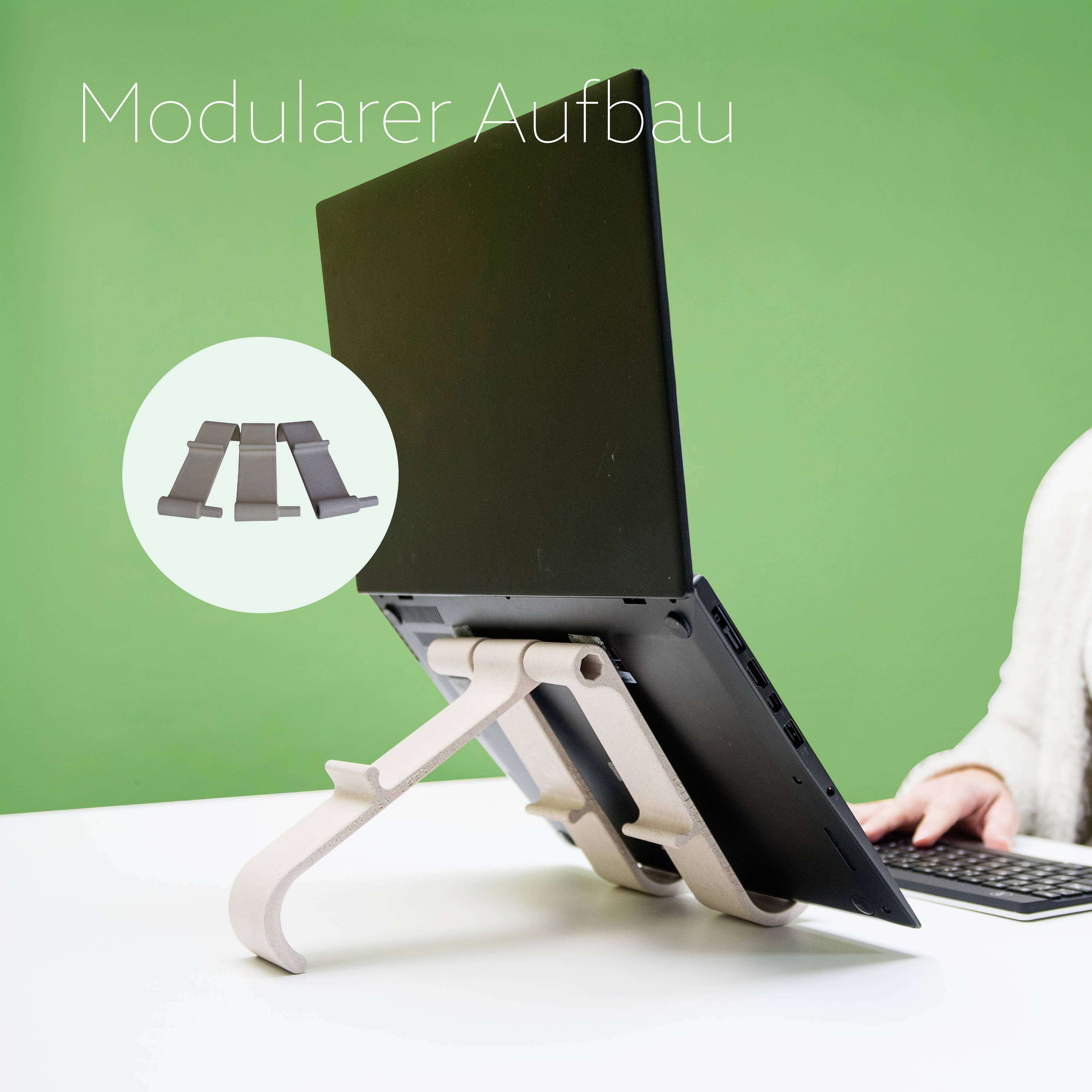 Laptop na regulowanym stojaku, prezentowany jako 'Modułowa budowa' na zielonym tle. Symbol stojaka w kole.
