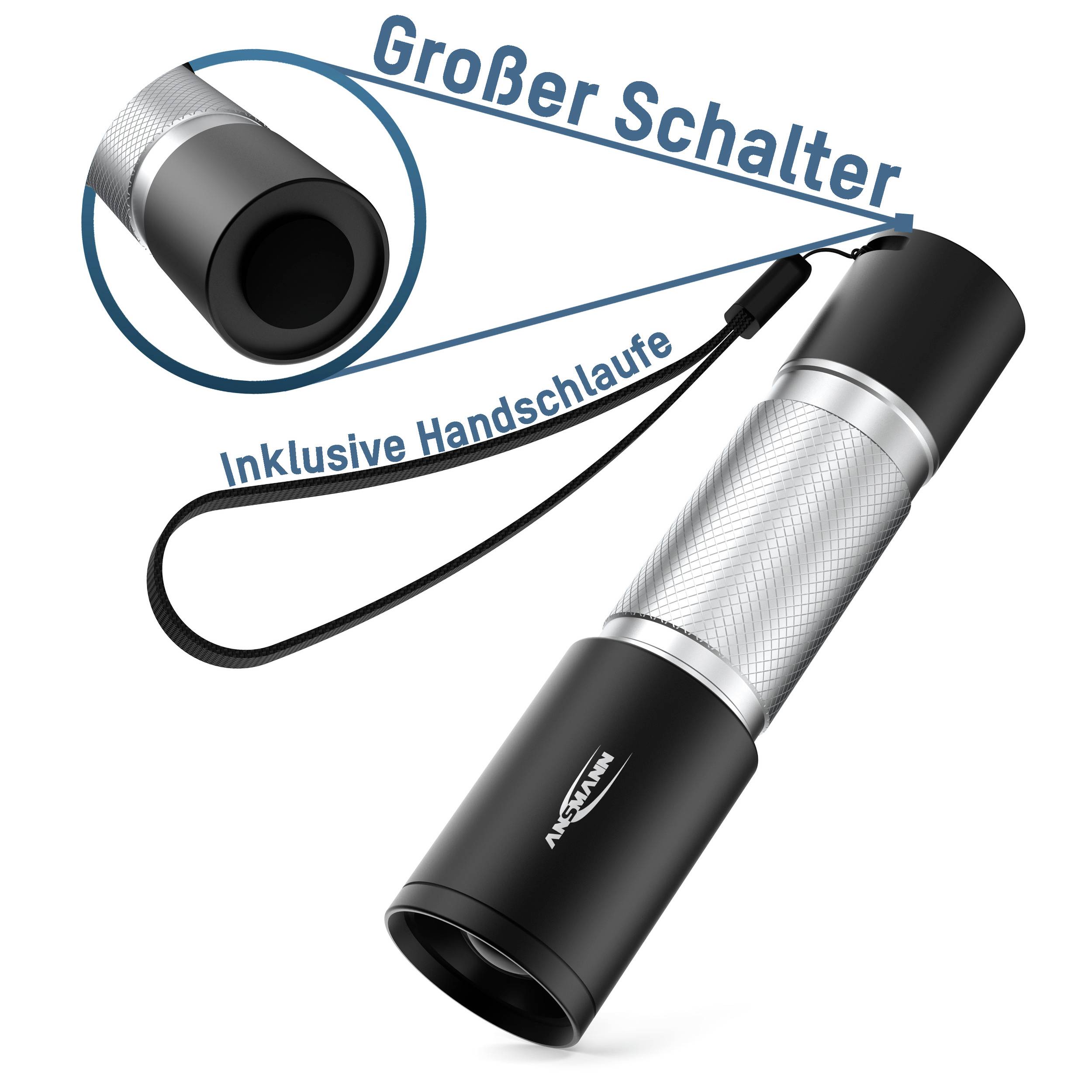 Latarka z dużym przełącznikiem i paskiem na rękę, w srebrno-czarnym designie, z napisem 'W zestawie pasek na rękę'.