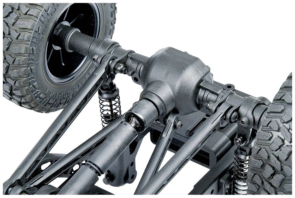 Zbliżenie podwozia samochodu terenowego, ukazujące zawieszenie, osie i opony z grubym bieżnikiem.