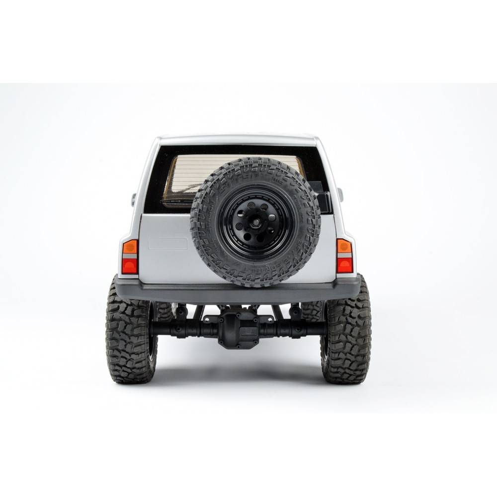 Biały samochód terenowy z dużym kołem zapasowym z tyłu, sfotografowany od tyłu, na białym tle.