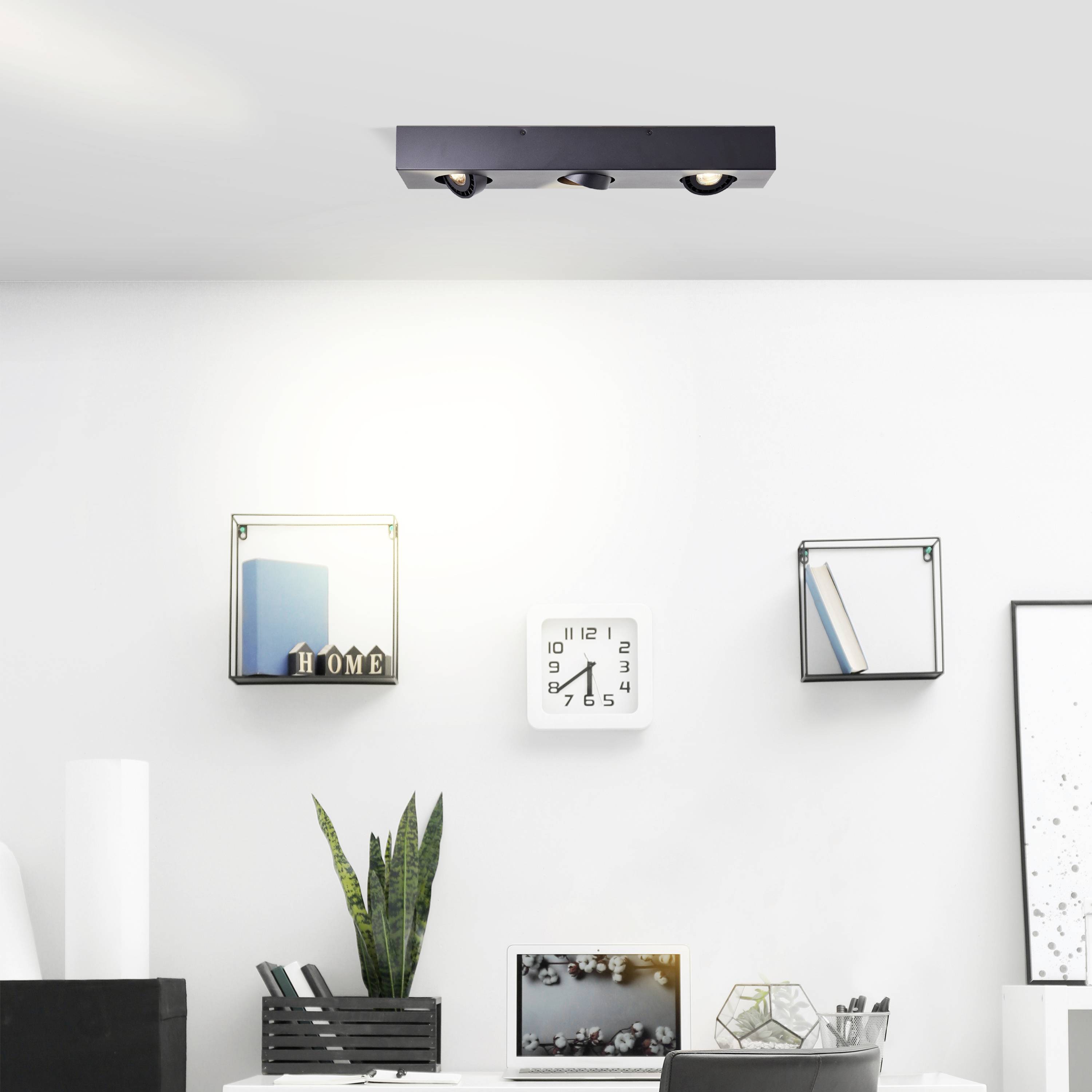 Nowoczesny salon w minimalistycznym stylu. Na ścianie widoczne są dwie książki na wiszących półkach oraz zegar.