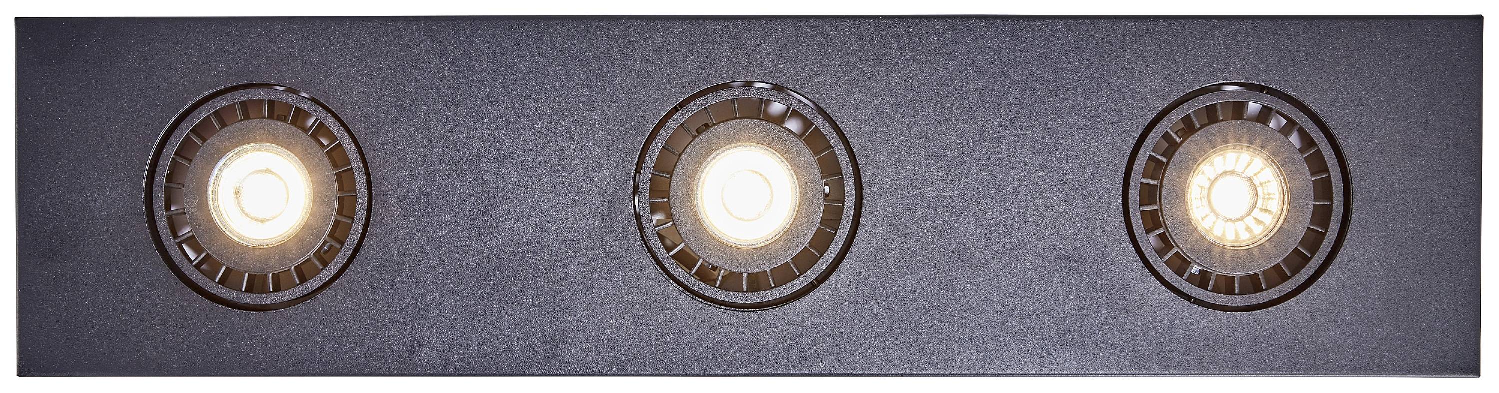 Trzy okrągłe, wpuszczone lampy sufitowe świecą w równomiernym wzorze na ciemnej powierzchni.