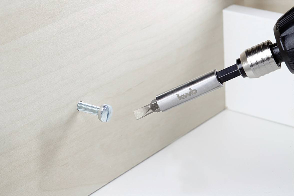 Wkrętak z końcówką wiertniczą wkręca śrubę w deskę drewnianą.