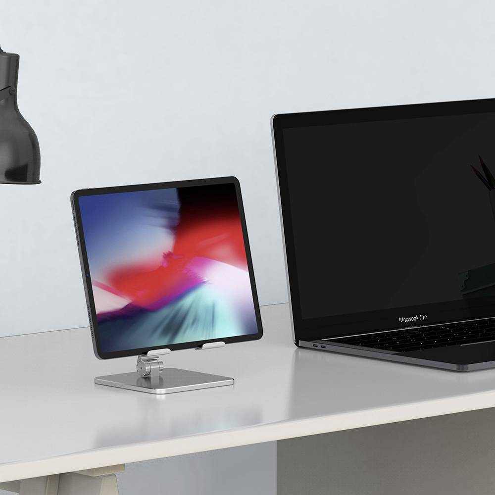 Laptop i tablet stoją obok siebie na stole. Ekran laptopa jest ciemny, podczas gdy tablet wyświetla wzór kolorowy.