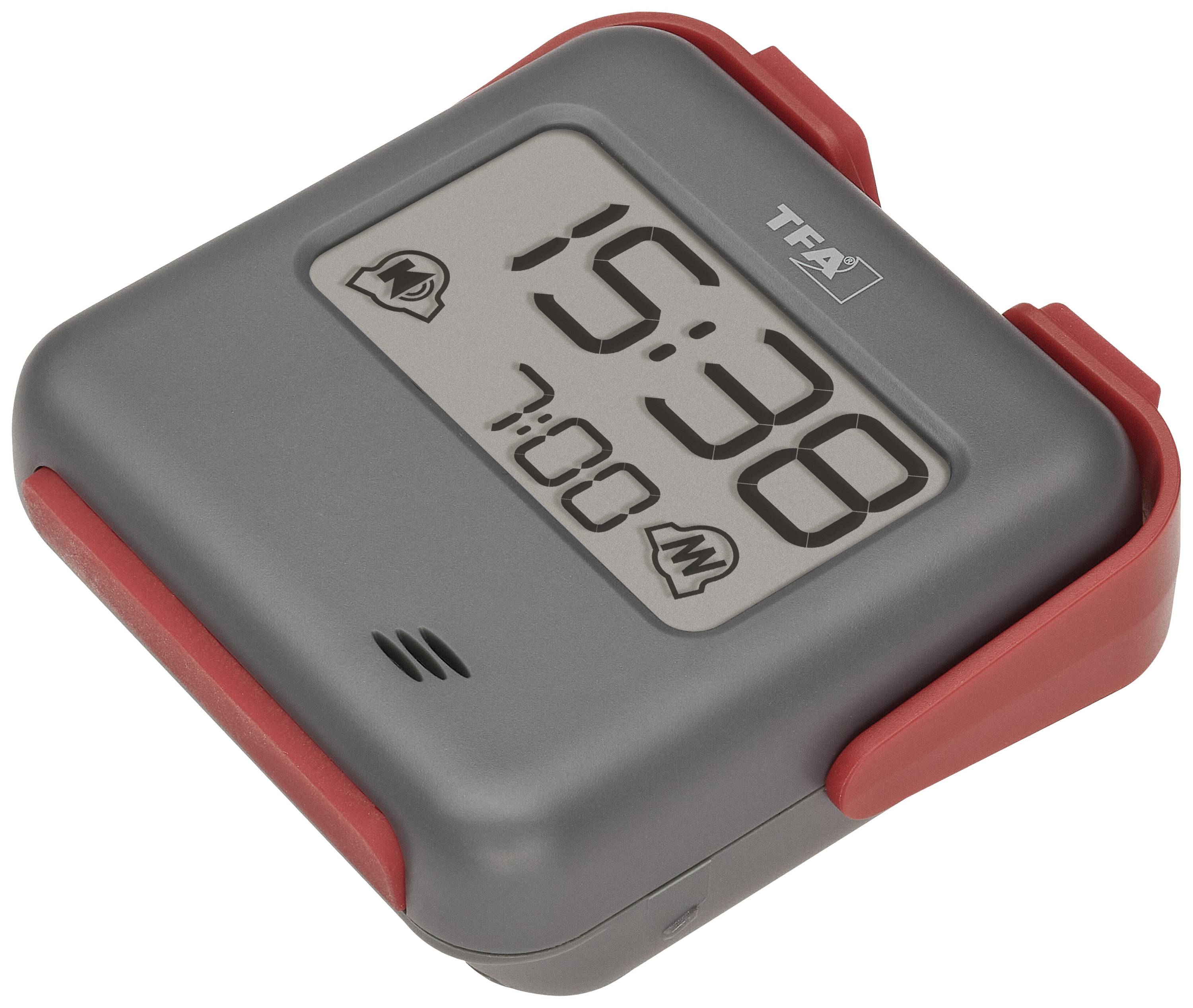 Szary cyfrowy budzik podróżny z czerwoną ramką, wyświetlający godzinę '15:38' oraz ustawioną godzinę budzenia '7:00'.