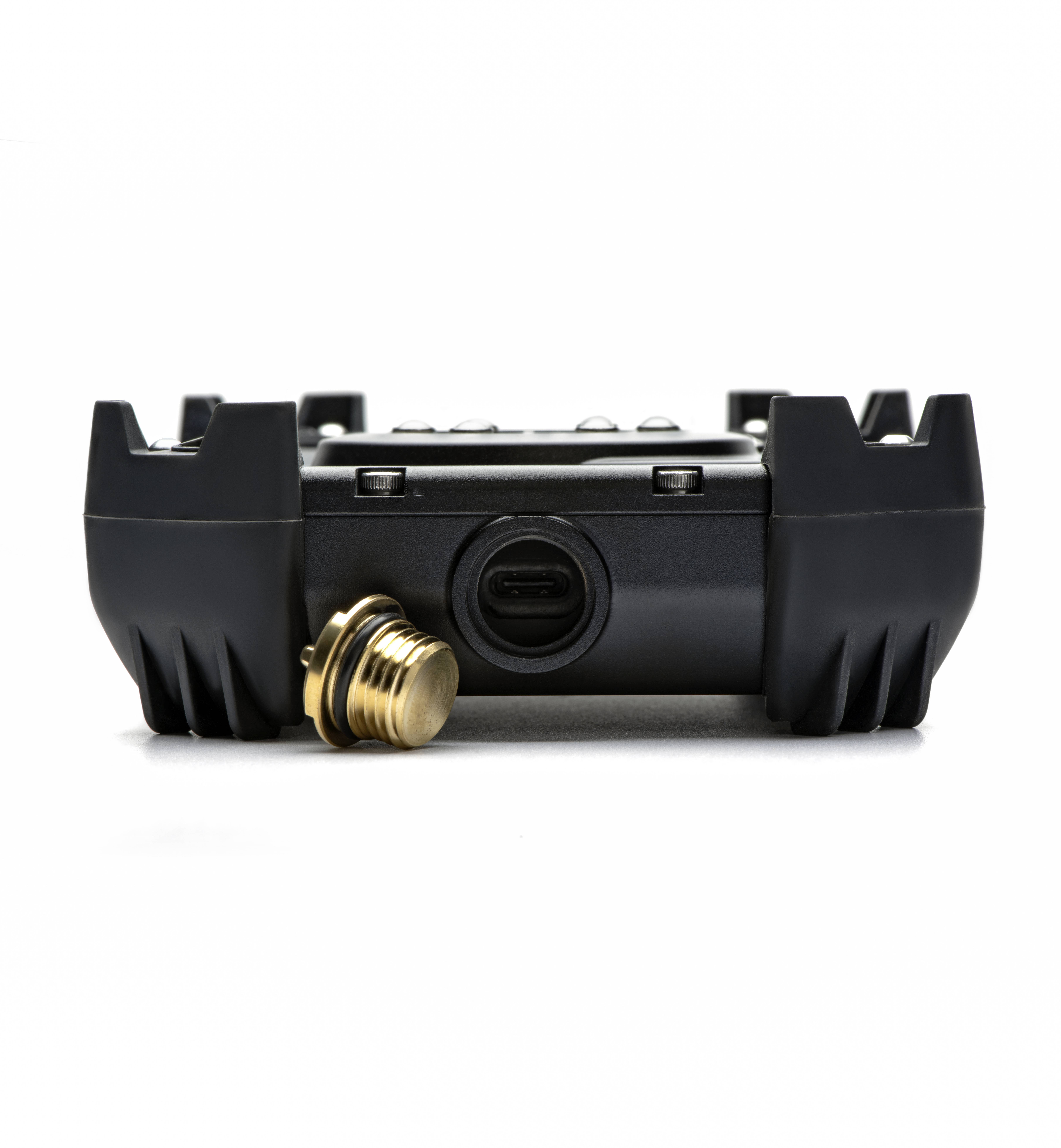 Czarny elektroniczny sprzęt z pozłacaną nakrętką, przedstawiający złącze USB-C. Widok od spodu.