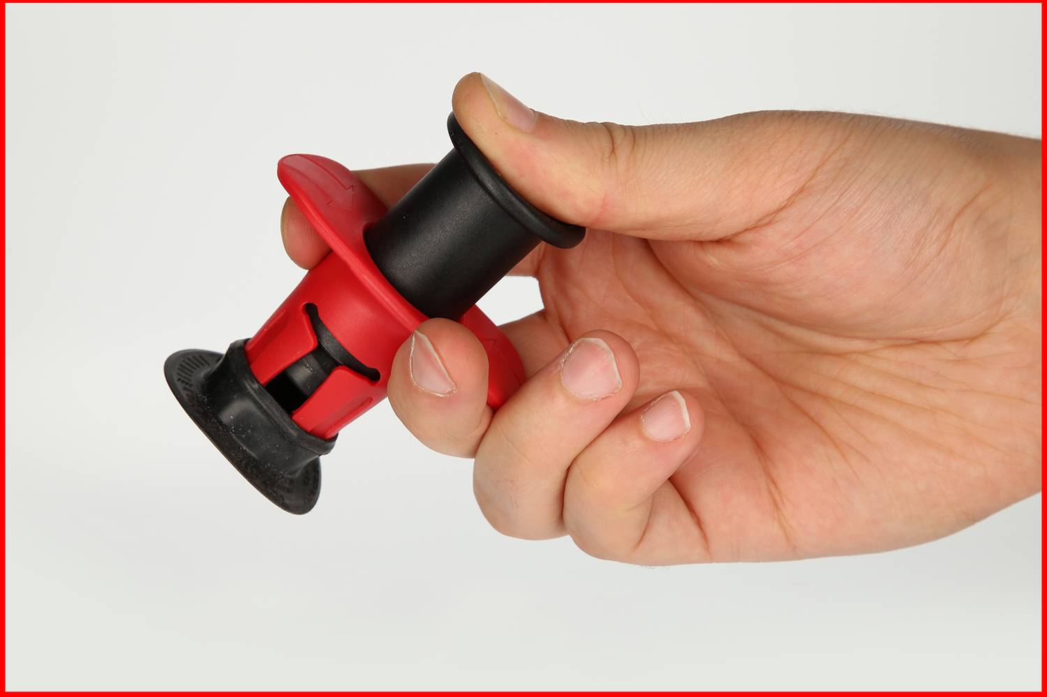 Dłoń trzyma czarny i czerwony przycisk z plastikowym klipsem.