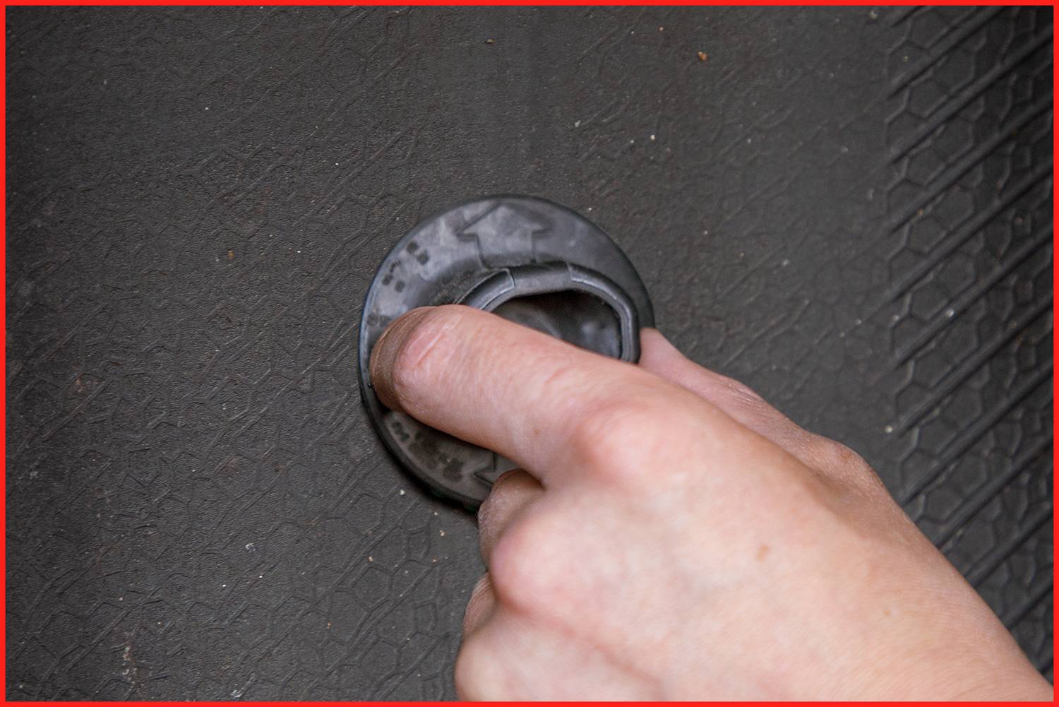 Dłoń obraca okrągłą klamkę na ciemnej powierzchni.