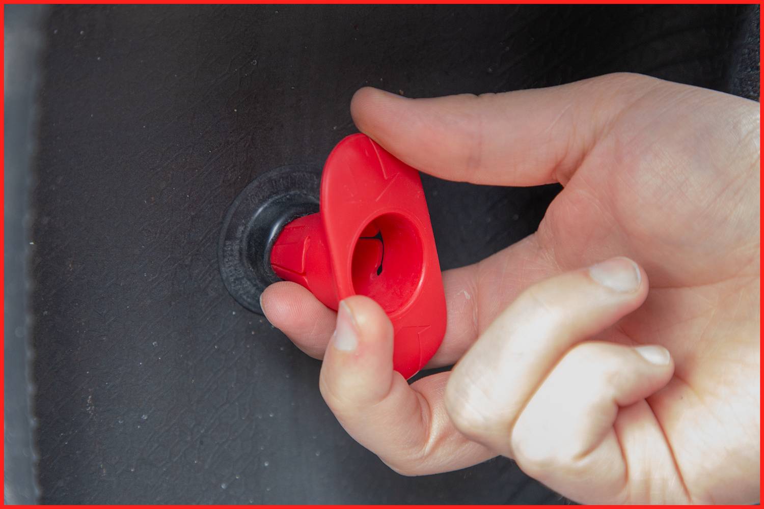 Dłoń obraca czerwony zawór na czarnej oponie, aby wypuścić powietrze.