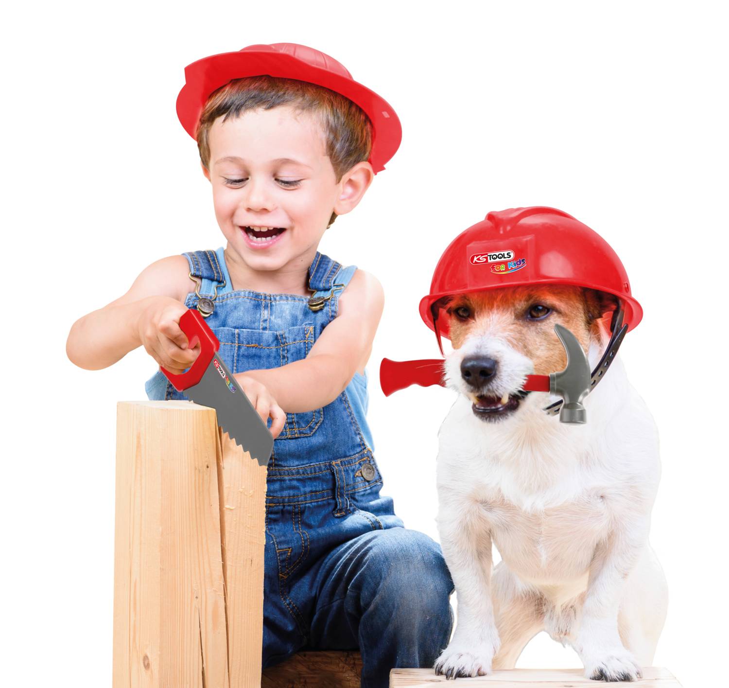 Chłopiec w czerwonym kasku piłuje drewno, obok niego pies w takim samym kasku, trzymający w pysku uchwyt narzędzia.