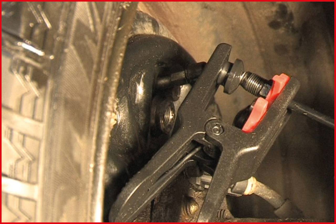 Zbliżenie narzędzia pracującego przy oponie lub metalowej powierzchni, prawdopodobnie podczas naprawy lub konserwacji.