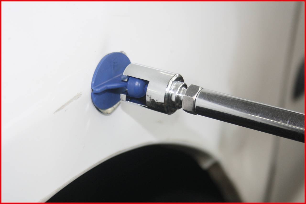 Zbliżenie niebieskiego narzędzia warsztatowego obrabiającego karoserię białego samochodu. Narzędzie jest przymocowane do prowadnicy.